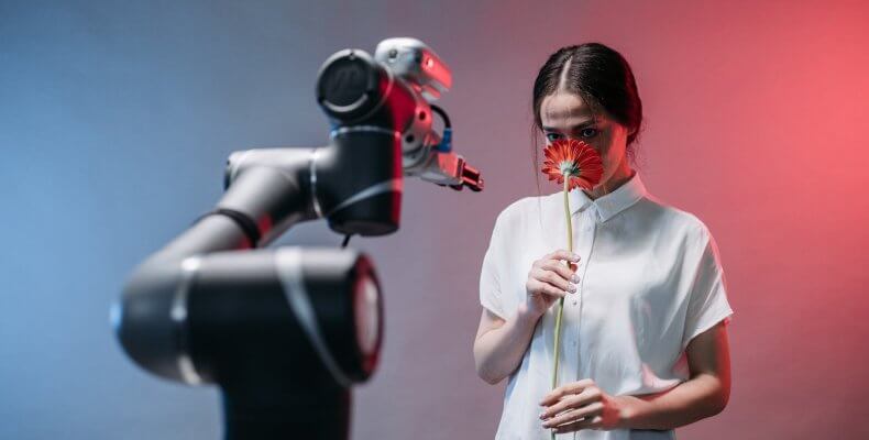a woman smelling a red flower while staring at a robot